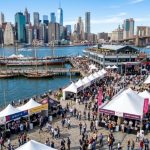 Aerial view of the NYC Wine and Food Festival at the Seaport waterfront with guests sampling food and wine at outdoor tasting stations