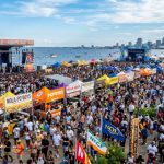 Thousands of food lovers gathered at the New Orleans Lakefront during the National Fried Chicken Festival 2026, with multiple music stages and vendor tents visible under an open sky