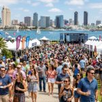 Crowds enjoying the Grand Tasting event at Embarcadero Marina Park North during the San Diego Bay Wine and Food Festival with the bay in the background